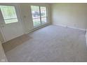 Open living room with neutral carpet, decorative front door, and large window providing ample natural light at 5416 Straw Hat Dr, Indianapolis, IN 46237