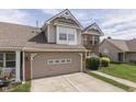 View of a two-story home featuring a brick-accented garage, vinyl siding, and a well-maintained lawn at 6542 E Edna Mills Dr, Camby, IN 46113