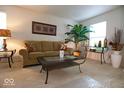 Comfortable living room with neutral carpet, featuring a glass top coffee table and house plants at 7737 Wolfgang Pl, Indianapolis, IN 46239