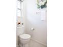 Well-lit powder room with fresh white fixtures, floral decor and window, adding a touch of elegance at 8317 Pine Branch Ln, Indianapolis, IN 46234