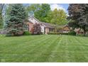 Charming brick and siding home featuring a lush front lawn and mature trees on a sunny day at 9885 Oakleaf Way, McCordsville, IN 46055