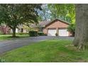 Brick home featuring an attached two-car garage and an asphalt driveway with mature trees and a lawn at 9885 Oakleaf Way, McCordsville, IN 46055
