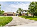 Charming two-story brick home with a large driveway and a well-maintained lawn surrounded by mature trees at 100 Wellington Rd, Indianapolis, IN 46260