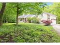 Scenic view of a ranch-style home nestled among mature trees and lush greenery at 13300 Fairwood Dr, McCordsville, IN 46055