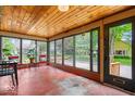 Bright sunroom with walls of windows, red floors and a wood paneled ceiling, perfect for relaxation at 1497 Clinton St, Noblesville, IN 46060