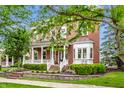 Beautiful red brick home featuring a covered front porch, mature trees, manicured lawn, and professional landscaping at 2037 Stanhope St, Carmel, IN 46032