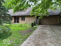 Home exterior featuring brick facade, attached garage and a concrete driveway surrounded by greenery at 310 S Shady Ln, Muncie, IN 47304