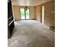 Spacious living room with natural light, exposed brick wall, and neutral carpet at 310 S Shady Ln, Muncie, IN 47304