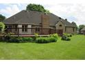 Wood deck in backyard with brick home, chimney, lush lawn and mature landscaping at 4288 Silver Hill Dr, Greenwood, IN 46142