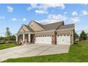 Beautiful brick home with a three-car garage, a well-kept lawn, and a cozy front porch on a partly cloudy day at 5032 Carmine St, Brownsburg, IN 46112