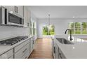 Modern kitchen with stainless steel appliances, gray cabinets, quartz countertops and a view to the backyard at 5032 Carmine St, Brownsburg, IN 46112