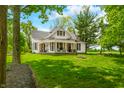 Beautiful two-story farmhouse with a covered porch and lush green lawn at 5335 W 550 S, Trafalgar, IN 46181