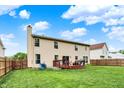 View of a backyard with a spacious lawn, wooden fence, and a deck with chairs and table at 6609 Fountain Springs Blvd, Indianapolis, IN 46236