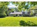 Charming ranch-style house featuring a lush lawn, mature trees, and manicured landscaping at 7035 Creekside Ln, Indianapolis, IN 46220