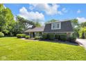 Charming ranch-style house featuring a lush lawn, mature trees, and manicured landscaping at 7035 Creekside Ln, Indianapolis, IN 46220