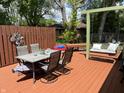 Outdoor deck area with a dining table and chairs, swing bench, wood fence, and leafy trees at 8206 Bull Run Ct, Indianapolis, IN 46227