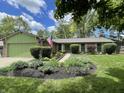 Charming one-story home with a green garage door, beautiful landscaping, and an American flag at 8206 Bull Run Ct, Indianapolis, IN 46227