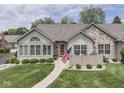 Inviting home featuring stone accents, manicured lawn, and cozy patio area at 1130 Deerbrook Trl, Greenwood, IN 46142