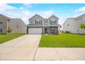 Inviting two-story home featuring a well-kept lawn, long driveway, attached garage, and neutral gray color scheme at 1893 Glenmoor Ct, Columbus, IN 47201