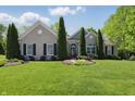 Charming brick home featuring a lush green lawn, manicured landscaping, and trimmed evergreens at 3815 Harrison Crossing Ln, Greenwood, IN 46142