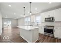 Bright, open-concept kitchen featuring white cabinets, stainless steel appliances, and a large kitchen island at 3936 Sterling Dr, Whitestown, IN 46075
