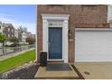 Close-up of a brick townhome facade featuring a blue front door with decorative trim and an attached garage at 6916 Havenmoor Pl, Indianapolis, IN 46250