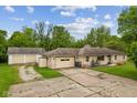 Home with stone facade, attached garage, detached garage, and a cracked concrete driveway at 6925 W State Road 128, Frankton, IN 46044