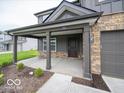 View of the covered front porch with stone columns and a dark-colored front door at 7517 Big Bend Blvd, Camby, IN 46113