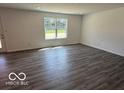 Open living room features durable wood-look flooring, neutral walls and a large window for natural light at 7517 Big Bend Blvd, Camby, IN 46113