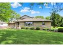 Landscaped front yard featuring mature trees and manicured bushes at 10036 E Troy Ave, Indianapolis, IN 46239