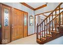 Welcoming foyer featuring hardwood floors, staircase with wood banister, and a stylish wooden front door at 12082 Old Stone Dr, Indianapolis, IN 46236