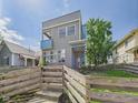 Striking two-story home showcasing unique architecture, a small balcony, and an inviting fenced-in front yard with steps at 1409 Spann Ave, Indianapolis, IN 46203