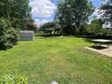 Sprawling backyard offers lush green space with mature trees and a storage shed, ideal for outdoor activities at 3023 Fairlawn Dr, Columbus, IN 47203