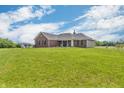 Rear view of a well-maintained brick home featuring a lush green lawn and a shed at 3319 E 700 N, Whiteland, IN 46184