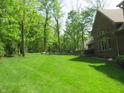 Expansive backyard with lush green grass, mature trees, and a cozy seating area at 4037 Oakleaf Dr, Zionsville, IN 46077