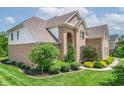 Charming brick home with lush landscaping, featuring various trees and decorative shrubbery at 4368 W Eagle Trce, New Palestine, IN 46163