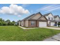 A beige vinyl-sided single-Gathering home with a two-car garage, lawn, and sidewalk near neighboring homes at 608 Fisher Creek Dr, Indianapolis, IN 46239