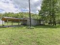 Exterior of a home with a covered carport, surrounded by a green lawn and mature trees at 6091 Mt Moriah Rd, Nineveh, IN 46164