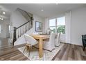 Bright dining room with wood floors, white chairs and a modern staircase leading upstairs at 6833 Jacone Dr, Brownsburg, IN 46112