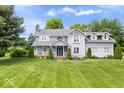Expansive front yard view of a gray two-story home featuring mature trees and green grass at 7056 E 171St St, Noblesville, IN 46062