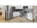 Modern kitchen featuring stainless steel appliances, white cabinets, and stylish backsplash at 7625 E 35Th St, Indianapolis, IN 46226