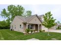 Charming exterior elevation of home featuring a covered porch, attached garage and green front lawn and plantings at 808 Heartland Ln, Brownsburg, IN 46112