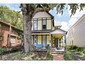 Inviting two-story home featuring a covered front porch with seating and mature trees at 847 N Park Ave, Indianapolis, IN 46202