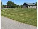 Landscaped lawn of gray brick home featuring a circular pattern and mature trees at 951 N Maiellen Dr, Greenfield, IN 46140