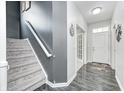 Bright foyer features hardwood floors, staircase with gray accent wall, and door leading to the living area at 10447 Pintail Ln, Indianapolis, IN 46239