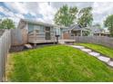 A cozy home with a wooden porch and steps, set amidst a lush green lawn and partially fenced yard at 1415 Lawton Ave, Indianapolis, IN 46203