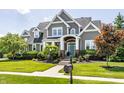 Inviting two-story gray home with manicured lawn, front porch, and blue front door at 1799 Hourglass Dr, Carmel, IN 46032