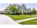 Attractive two-story gray home with lush lawn, mature trees, and manicured shrubs at 1799 Hourglass Dr, Carmel, IN 46032