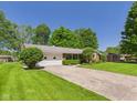 Quaint ranch-style home with attached garage, mature trees, and large front yard at 25 N Mustin Dr, Anderson, IN 46012