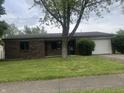 Charming single-story brick home featuring a well-maintained lawn and an attached one car garage at 3055 Pawnee Dr, Indianapolis, IN 46235